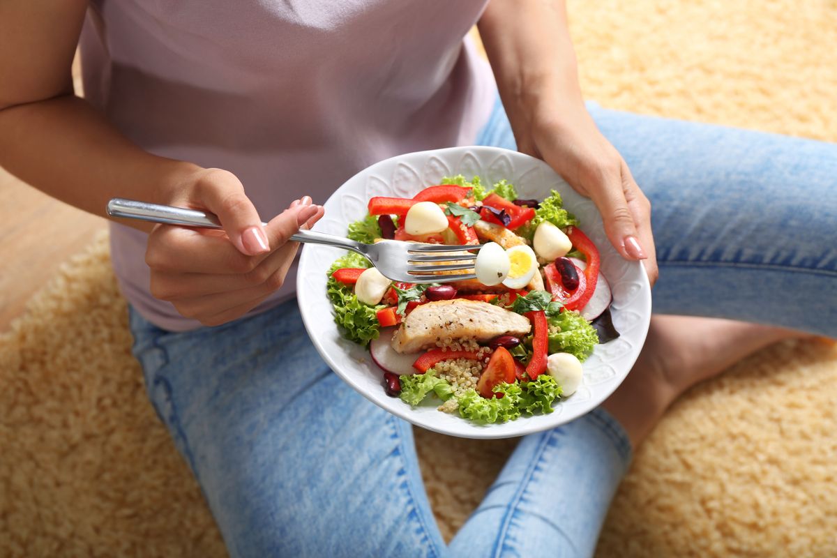 Young,Woman,Eating,Tasty,Chicken,Salad,With,Vegetables,While,Sitting