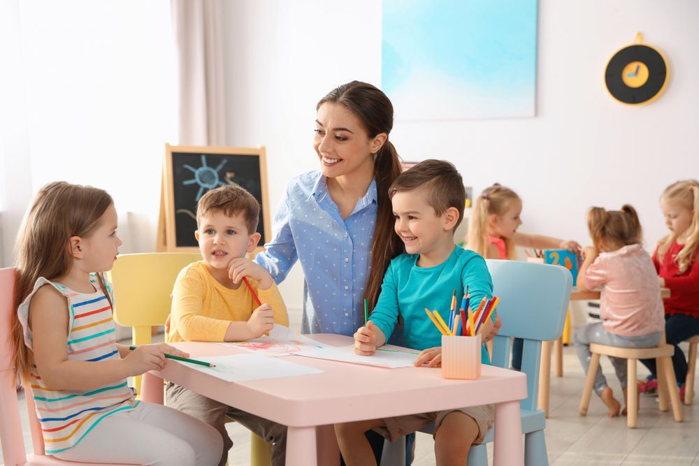 Little,Children,With,Kindergarten,Teacher,Drawing,At,Table,Indoors.,Learning