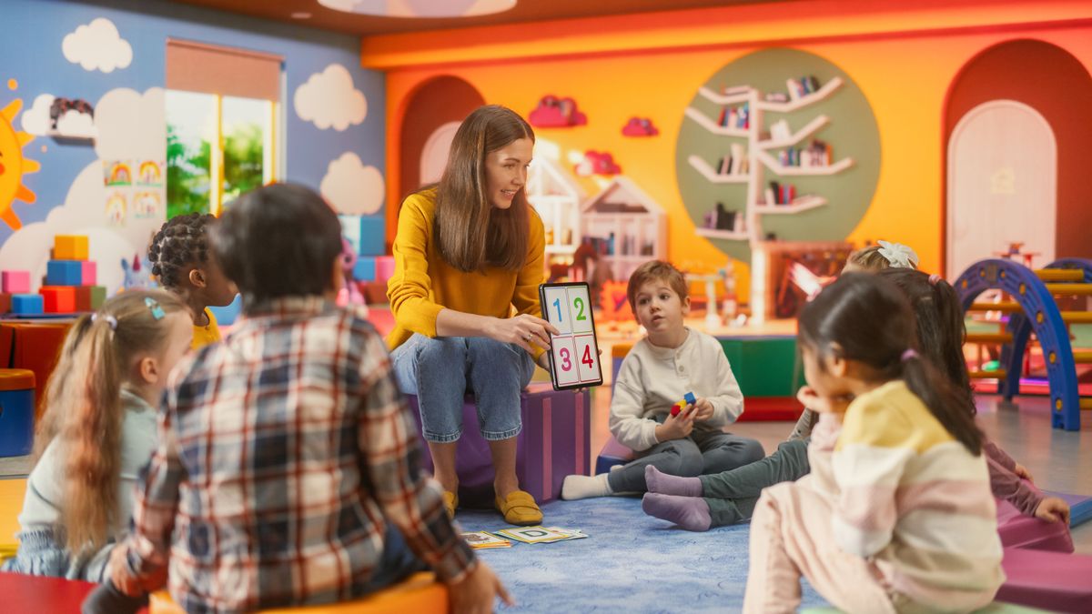 Happy,Professional,Kindergarten,Teacher,Using,Tablet,Computer,To,Show,Numbers